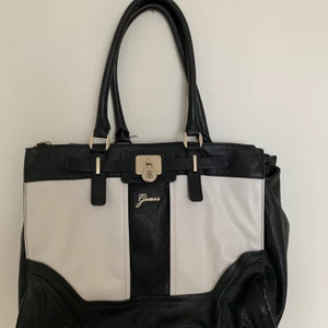 Guess, väska - En svart, vit och guldig väska från märket Guess. Köpt i en Guess butik och säljer pågrund av att jag aldrig använt den. Den är stor och har många fack, man får plats med en dator i den plus massa block.🌸💖 Vid intresse kontakta gärna, frakt ingår i priset🥰