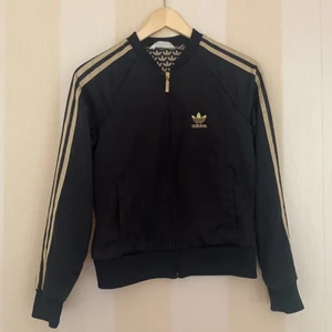 Adidas tröja med dragkedja - Adidas tröja, svart och guldig med adidas tryck på insidan. Står storlek 38 men jag tror att det kan vara barnstorlek men passar xs och S.