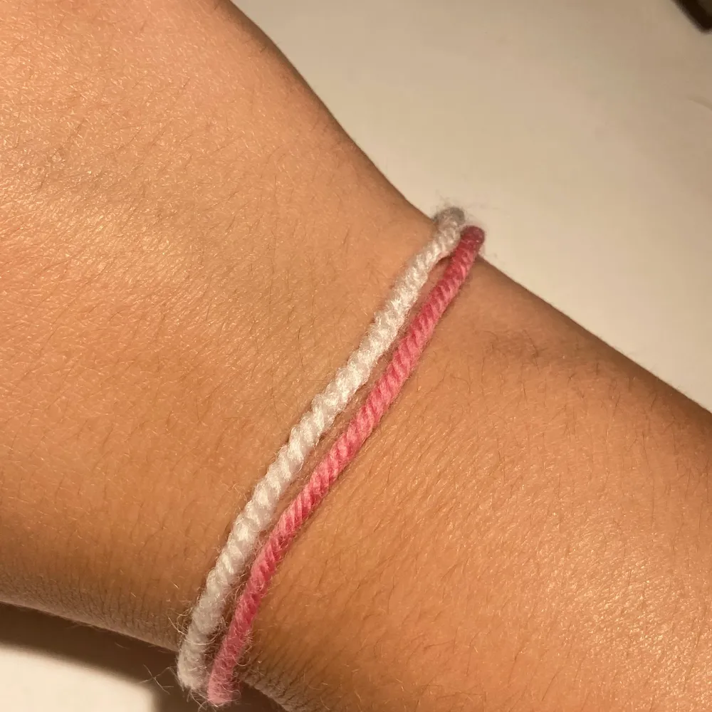 Vit &rosa armband gjort av garn! Man får knyta den själv. Accessoarer.