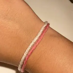 Vit &rosa armband gjort av garn! Man får knyta den själv