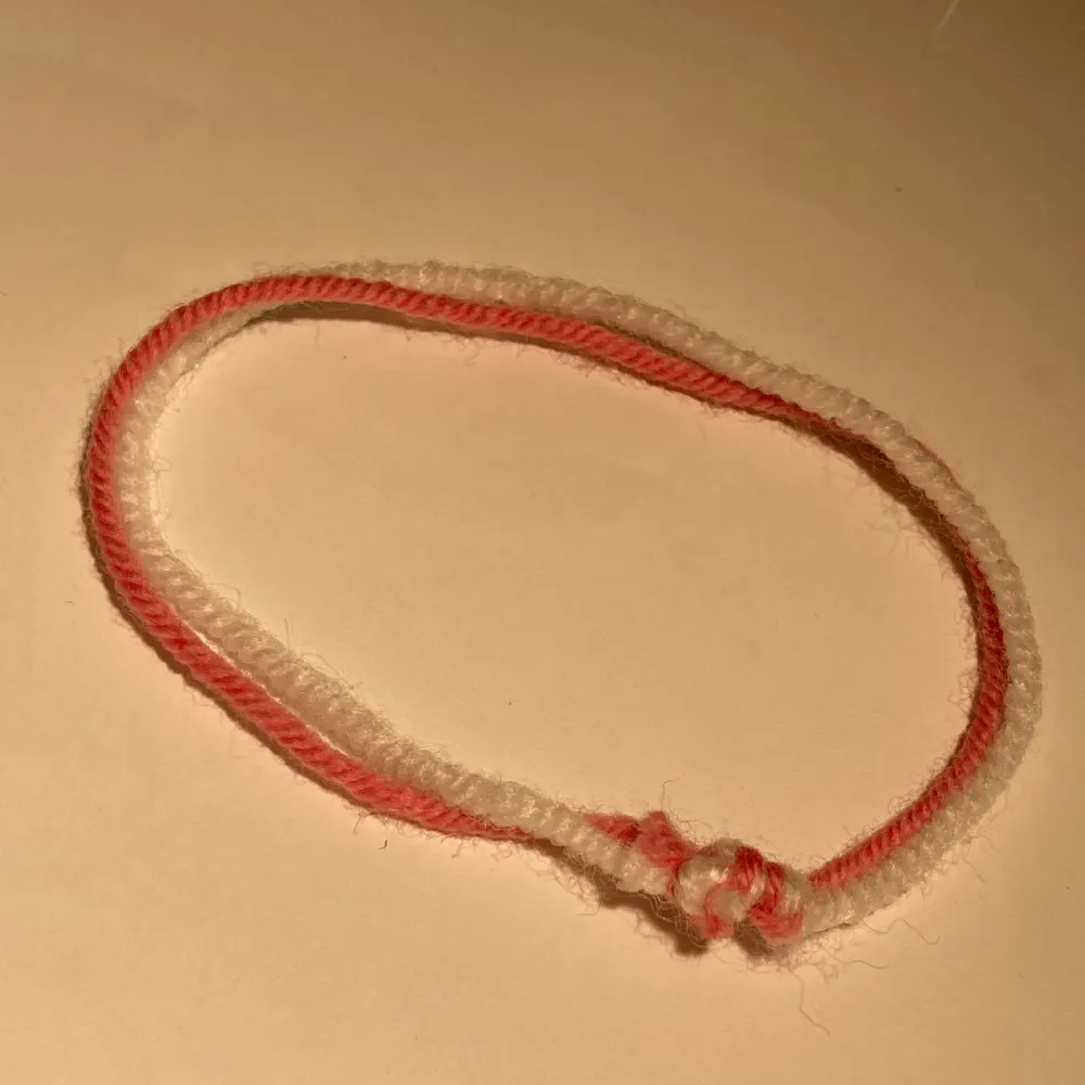 Vit&rosa armband gjord av garn, man får knyta den själv! . Accessoarer.