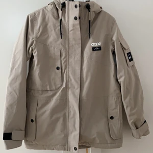 Dope skidjacka storlek XS - Beige skidjacka från Dope. Vaderad, vidtät och vattentät. 1 år gamla och enbart använd 5 gånger. Stor i storleken, jag är 165 och har storlek XS i jackan. 