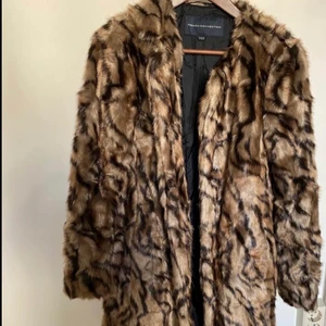 Kappa i fuskpäls strl 34 - Kappa i fuskpäls från French Connection, fickor framtill. Strl 34 (UK 8). Väldigt mjuk och len päls. I nyskick. Hämtas hemma hos mig på Kungsholmen 