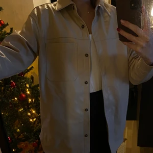 Beige Skinnskjorta/jacka - En skinnskjorta i beige från HM. Funkar lika bra som en vår/höstjacka. Två fickor på vardera sida. Använd enbart ett par gånger. Strl S. Köparen står för frakt