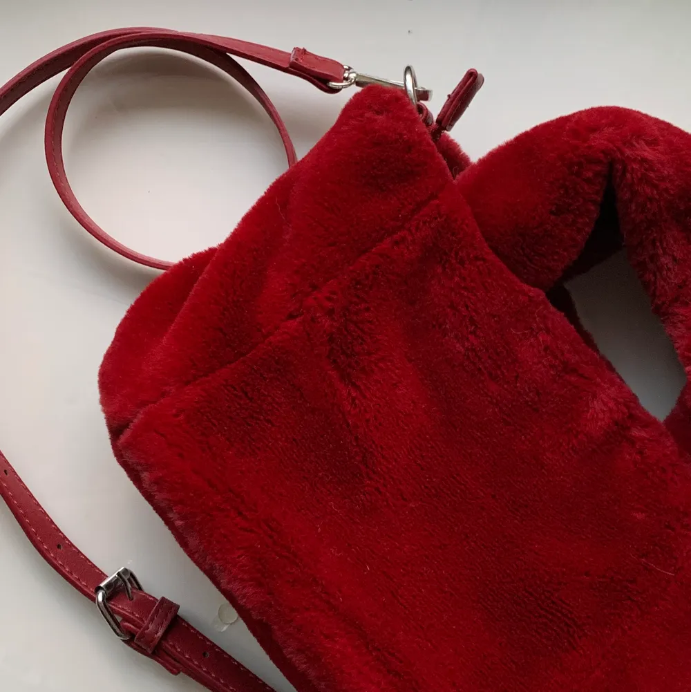 En röd supermjuk ”päls”-väska från Bershka. Den har en avtagbar justerbar rem och stängs med en fungerande dragkedja. Använd endast ett fåtalgånger så är som i nyskick. FRAKT tillkommer från 66kr. . Väskor.