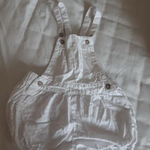 Hängselshorts från Newbie - Har två knappar på banden som man kan ändra storlek på när man sätter ihop dom. Har något lilla/rosa mönster på men är svårt att se. Använt 1 gång så är i ett bra skick men skrynklig.