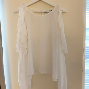 Vitblus - En vit blus men volanger/hål över axlarna. 