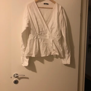 Vit topp med volang nertill  - Från Ginatricot. Använd ett fåtal gånger. Har ett resår band i midjan. 