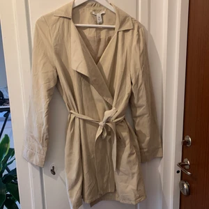 Beige kappa - Beige, tunn kappa från Nelly. Denna säljs inte längre! Medellång modell. Frakt tillkommer eller möts kring Hägersten, Stockholm 🤗