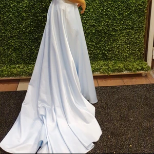 Bal/fest klänning  - En väldigt elegant balklänning använd 1 gång. Ett långt släp med korsade band på ryggen. På släpet finns det en loop som man kan sätta runt handleden för att lättare kunna ex dansa i klänningen. Klänningen är ljusblå och är väldigt skön att ha på sig. Den har stora fickor man man ex kan lägga son mobil i(det man har i fickorna syns inte utifrån, det gäller också öppningen till fickorna, de syns ej). Klänningen är använd 1 gång.       Klänningen är köpt för 6000kr, pris kan diskuteras