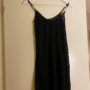 Säljer en svart klänning i spets som nästan går till knäna, lite högre upp. Köpt på secondhand, stl S.