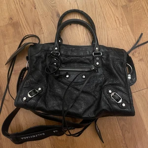 Balenciaga väska  - Intressekoll på min Balenciaga city bag, storlek small. Inte säker på att jag vill sälja så vill se vad jag kan få för den isåfall!! Nypris 20000. Inte det vanliga bandet utan köpte till bandet med text på, därav priset på väskan. Dustbag ingår, kan skicka fler bilder om de önskas!! Använd men bra skick. Buda i kommentarer. Går inte ner mer än 14 000