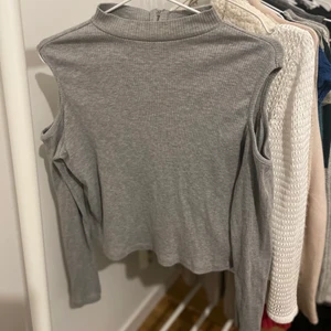 Grå tröja - Grå ribbad tröja med axelhål! Denna är i bra skick och går att använda både till vardags och vid festligare tillfällen🙌 tröjan är i storlek L men passar även mig som vanligtvis har S. Köparen står för frakt