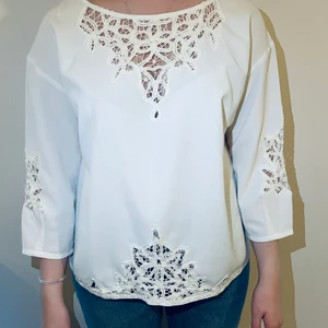 Vacker blus från Wera med underbar rygg  - Vacker blus från Wera med underbar rygg med knappar Storlek: 44 men som 40-42 Material: Polyester 100% Spets i bomull 100% Skick: Finns två hål i spetsen (på en ärm och dekolletage) Se bilder. Färg: Off white 