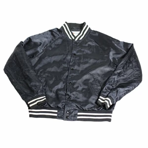 Baseballjacka - En riktigt Nice svart och vit varsityjacka/bomberjacka/collegejacka etc. Som har riktiga 80-talsvibbar. Den är gjord i nylon och därför perfekt som skydd mot vind och regn. Är från usa och troligtvis använd av collegeungar på 80-talet.