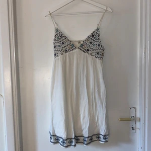Kort, vit bohemisk klänning  - Står stolek 42 men är som S. Justerbara band och är inte see through. Använd ca 2 gånger och är i fint skick, köparen står för frakt.