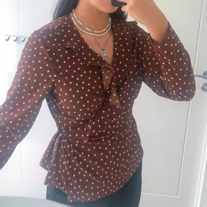 Prickig blus - Säljer denna prickiga blusen. Den är använd några gånger men den är som ny. Den har snören som man knyter runt midjan och den är lite v-ringad. Säljer den för 50kr + frakt om man inte kan mötas upp i Gbg.