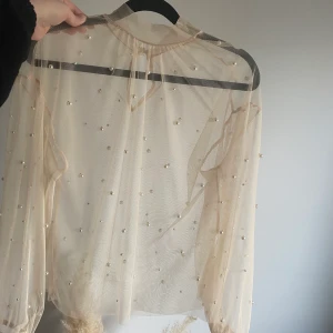 Topp med pärlor - Topp från Gina tricot i nyskick. Färgen är en rosa/beige ton, Superfin med en spetsbh under eller linne om man föredrar det. Storlek S/M. Passformen är lös. Kom och köp tröjan som ger lite extra spice till vardagsoutfiten! 🥳 kan mötas upp i Stockholm/Barkarby, annars betalar köparen frakt 🌻