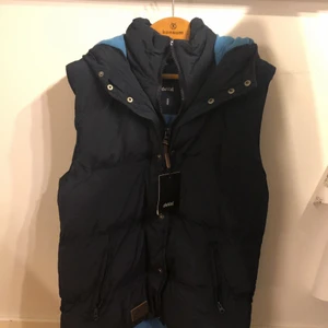 deVal Väst oandvänd - Snygg väst, mörkblå färg, med luva. Storlek medium. Passar perfekt nu innan vårvärmen slår till. Inne fleece foder.