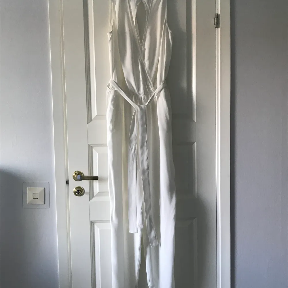 En flowy vit jumpsuit med öppen rygg. Detta är en helt  ny oanvänd jumpsuit köpt av min mamma. Den är lite see-through vilket hon inte gillade.. Klänningar.