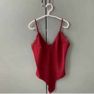 Vinröd body - Fin v-neck body med spets över brösten o storlek S. Hade varit så fin till en svart kjol på kvällen!!