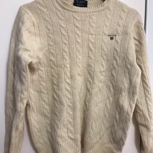 Gant tröja - - Vaniljfärg - Flätstickad - Tröjans skick syns tydligt på bild - Passar S-L (Strlk L på tröjan)  Kan skickas mot frakt, fraktpriset står i nästa steg 📦  Alla betalningar sker tryggt via Swish. 🤝  Inga returer, plagget säljs i befintlig skick enligt bild och beskrivning. ❌