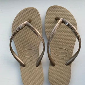 Flipflops - De perfekta skorna till sommaren som är i en beige färg och har guldiga detaljer. Inte särskilt andvända utan bara lite slitna längstfram. Det är storlek 35/36 och har en jätte skön passform.