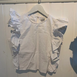 Vitt linne Gina Tricot - Vitt linne i bomull med volanger på sidorna, både fram och bak!