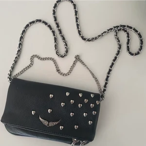 Zadig väska - Har nu bestämt mig för att sälja min älskade zadig väska. Säljer då jag vill köpa en annan som rymmer mer. Det är bara att höra av sig vid frågor. Säljer för 1500 eller högsta bud. Vid snabb affär kan jag gå ner i pris till 1200!🥰 Hjärtana har blivit super super lite rostiga men inget man tänker på alls❤️.