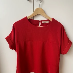 Fin röd dräkt från Japan - Fin röd dräkt med kjol och topp. Märke Unaca. Inköpt i Japan för några år sedan men aldrig använd. Storlek 38. Materiallapp är på japanska så vet ej material. Dock härlig lite lyxig känsla i tyget som inte skrynklar. Aldrig använd och i bra skick förutom en fläck/skiftning i tyget vid ena ärmen på toppen, se bild. Den syns mindre i verkligheten och jag har inte försökt ta bort den.