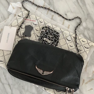 Zadig & Voltaire rock väska  - Svart Zadig Voltaire rock väska i höjd 15 cm och bredd 27cm. Väl använd och tecken på slitage finns på metallen samt vingarna (se bild) men har fortfarande mycket kvar att ge🖤🖤 700kr+66kr spårbar frakt, annars finns den att hämtas upp i centrala Göteborg 🖤🖤 först till kvarn, den som betalar först🖤