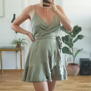 Ljusgrön klänning i storlek 40 - Ljusgrön silkesklänning i omlottdesign med volanget nertill, stängs med dragkedja i ryggen. Från Boohoo i storlek 40, jag på bilden är 170 cm lång och brukar vanligtvis ha storlek 36/S i klänningar.