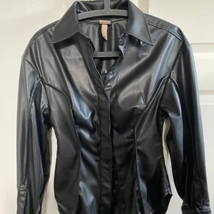 En kavaj med knappar - En kavaj av skinn och knappar. Sitter pösigt på axlarna och tajt vid midjan. Använd en gång.