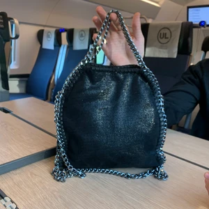 Stella macartney  - Stella macartney likande väska! Vill gärna få såld så möts gärna upp nu i helgen eller postats nu ikv eller imorogn! Så fin i skicket och köpt här på plick, väskan är svart glittrig och har en rund cirkel på kedjorna, den är helt blank💞💞 köp direkt för 1000