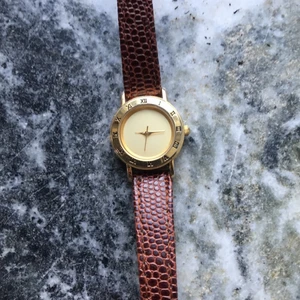 Klocka - dam - Guldklocka med läderarmband. Begagnat, armbandet är lite skadat. Hittar inte märket, batteribyte behövs.