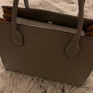 Grå handväska - Denna handväska är köpt i Österrike för ca 1 år sedan, vet tyvärr inte märket. Nypris: 1000kr. Min mamma som fått i present men aldrig använt. Är i nyskick! Priset kan diskuteras. Ganska liten men den har flera fack. Skriv privat för fler bilder💗