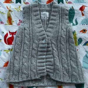Ljusgrå kabelstickad väst - Säljer min jättefina gråa kabelstickade väst i storlek S/M jättefin till jeans eller kostymbyxor att ha med eller utan tshirt under!