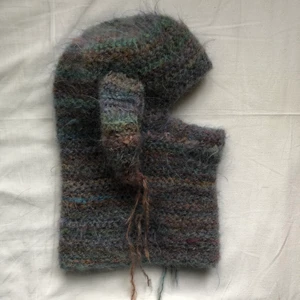 virkad balaklava - Handgjord virkad balaclava med öron gjord av mig. Den är gjord med ett flerfärgat fluffigt/hårigt mohair garn. Fungerar som mössa och halsduk i ett. Man kan även bära den under hakan, så man kan äta och dricka i den :) Köparen står för frakt❣️