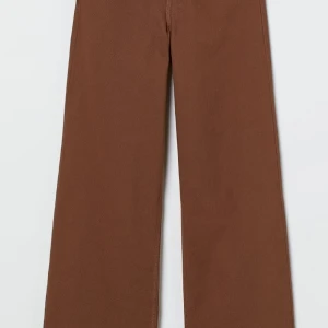Hög midjade bruna byxor  - Är ett par bruna långa 5-ficksbyxor i strechig bomullstyg, byxorna är högmidjade och vida, raka ben , har också gylf med en dragkedja och knapp 
