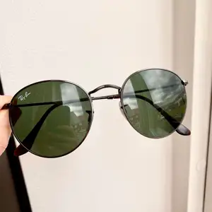 Snygga Ray-Ban solglasögon i den populära modellen ”Round” storlek M. Grönt glas och båge i gun-metall. Nyskick! 