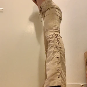 Beiga lågmidjade byxor  - Lågmidjade byxor i storlek XS/S med snörning fram och på sidorna. Fickor finns bak. Tyget är lent, likt mocka. Säljer då dem tyvärr inte kommit till användning. 