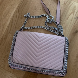 Söt axelremsväska  - Smidig ljusrosa väska. Ca 30 bred. Lite färg från jeans på insidan, alltså ingenting som syns vid användning. 3 fack varav ett mindre med dragkedja. Stängs med magnetknapp.