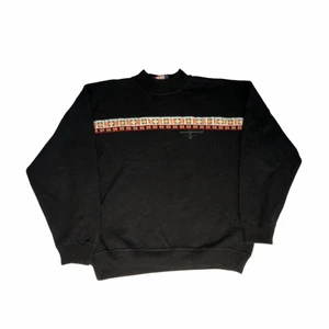 Moutgourney - Vintage sweatshirt - En fin svart sweatshirt som har ett lite stickad känsla. Med ett väldigt fint 80-talinspirerat tryck längs bröstet. Köpt på en butik i Florida.