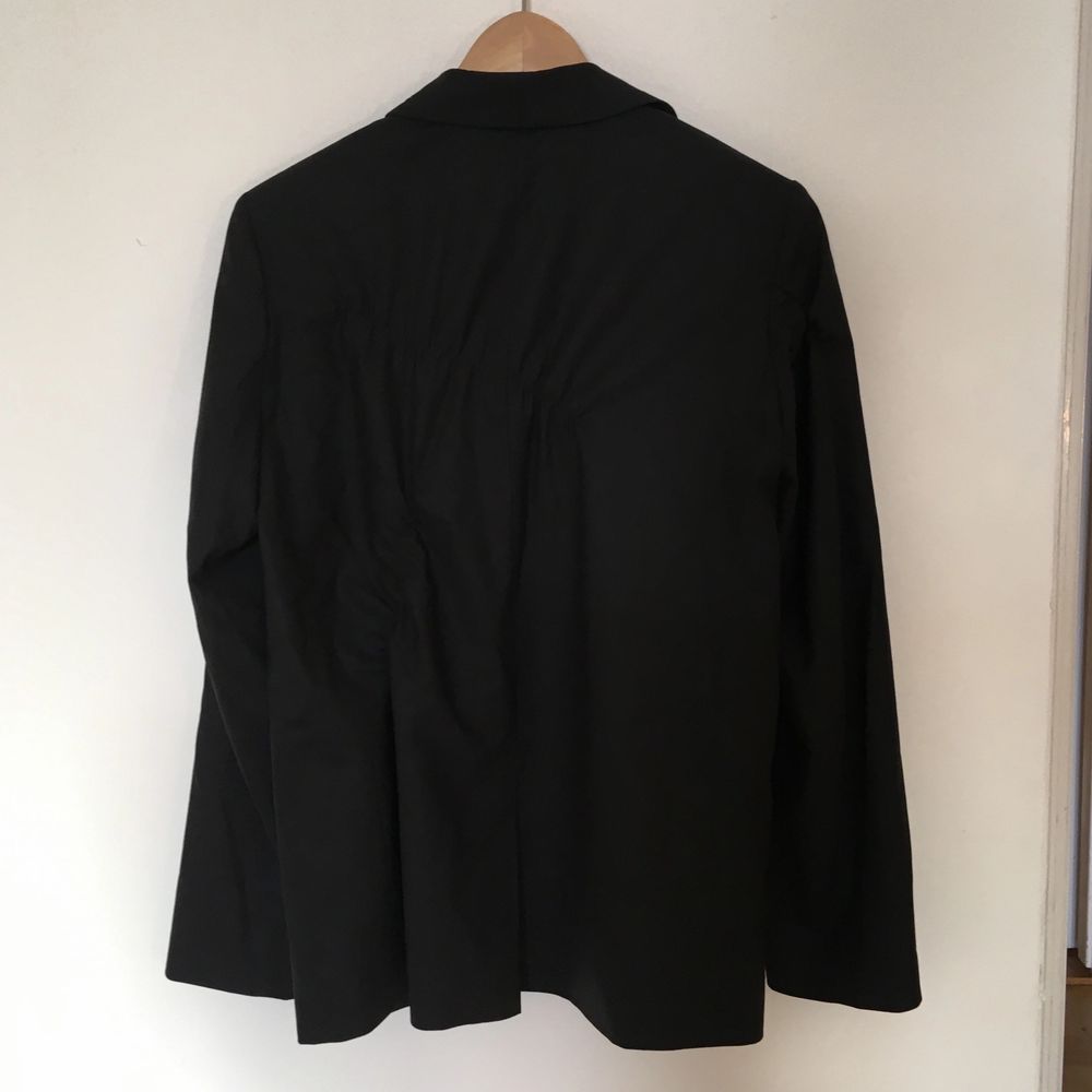 En assymetriskt veckad svart kavaj i tunn ull från Cos, så kallad sommarull som fungerar bra och andas när det är varnt. Storlek 38, oversize modell med fint fall i tyget. Jag har fler bilder på passformen som jag kan skicka! Superfina detaljer och jättefin kvalitet, den här förtjänar att bäras!. Jackor.