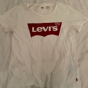 Levis T-shirt  - En vit T-shirt med det vanliga röda trycket ifrån Levis. Använt ett fåtal gånger. Köpare står för frakten (66kr och går att spåra eller att vi tillsammans bestämmer ett billigare pris för frakt)💕