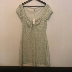 Sommarklänning från Nelly  - En pistachgrön blommig klänning från Nelly. Helt oanvänd med etiketten kvar. En kort klänning som slutar på mitten av låren. Sömmar på sidorna för finare passform. 