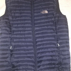 The North Face Dunn väst - Jag säljer en äkta The North Face väst som är marinblå. Västen är i väldig bra skick, den är nästan oanvänd. Den väger nästan ingenting, den är vind tålig och vatten avisande. 