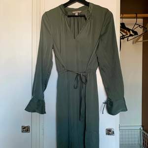 En silkesliknande klänning jag enbart använt vid ett tillfälle, midjan tas åt med snörning och snörning finns runt handlederna. Super härlig, lite grå/grönaktig.