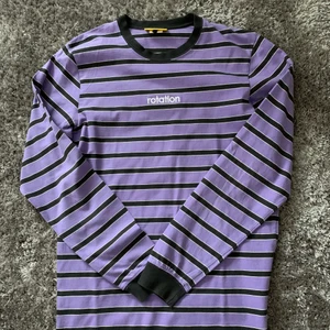 Lila o svart tröja - Säljer en randig tröja i tunnare sweatshirt material som inte kommer till användning längre. Storleken är oklar men sitter bra på mig som brukar ha S/M. Tröjan är i mycket bra skick! 