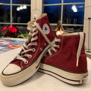 Vinröda converse  - Trendiga höga Converse i vinröd färg, fina till våren! Skorna är använda, se bilder, men inga hål eller skador. Skriv för fler bilder eller frågor💕 Kolla gärna in mina andra annonser för fler Converse🥳